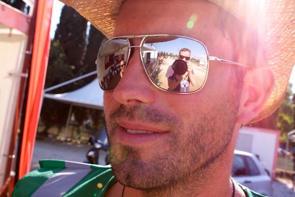 Un hombre con un sombrero de paja que refleja al fotógrafo en sus gafas de sol