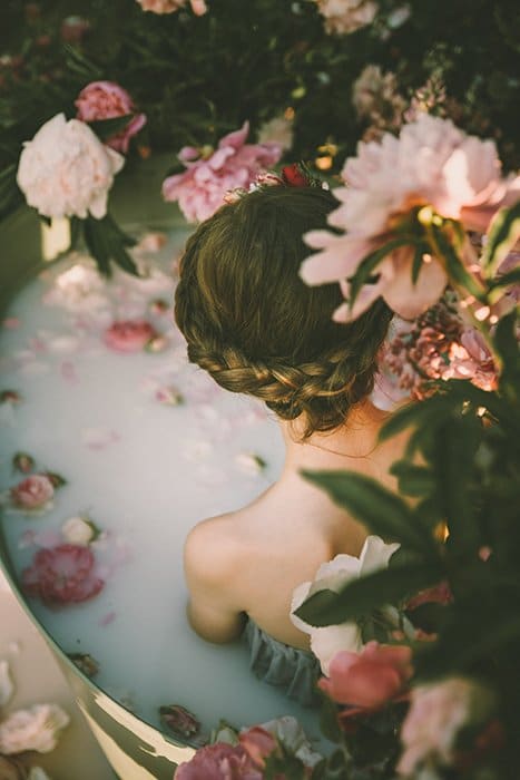Una niña en una bañera rodeada de hermosas flores.