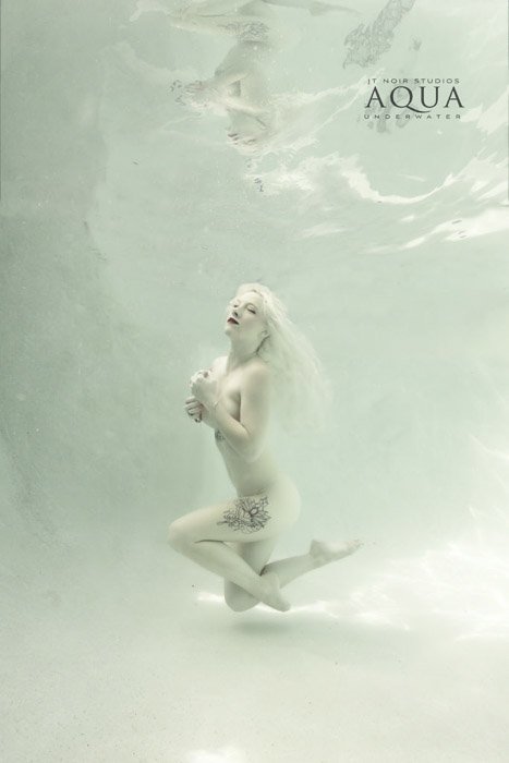 Retrato submarino atmosférico de un modelo femenino posando bajo el agua