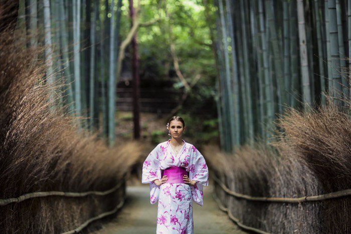 Un retrato de vacaciones de un modelo femenino en traje de estilo asiático posando en un bosque