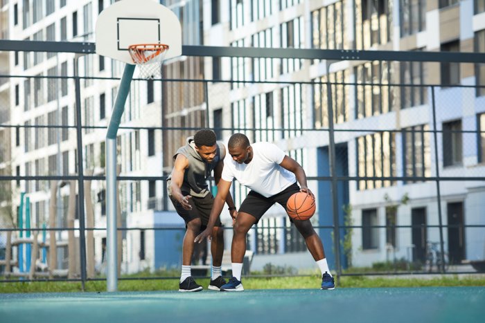 Toma de acción de dos hombres afroamericanos jugando baloncesto en la cancha al aire libre