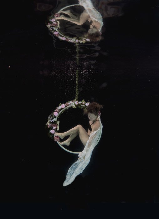 Foto hermosa y atmosférica de una niña posando bajo el agua en un aro