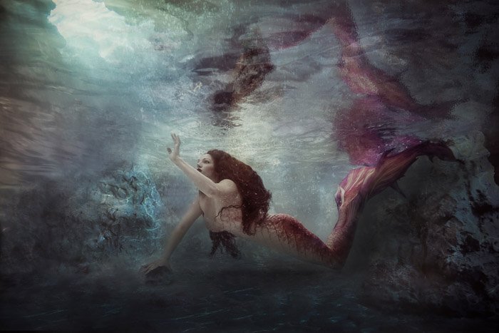 Hermosa y mística fotografía submarina de una niña sirena nadando bajo el agua