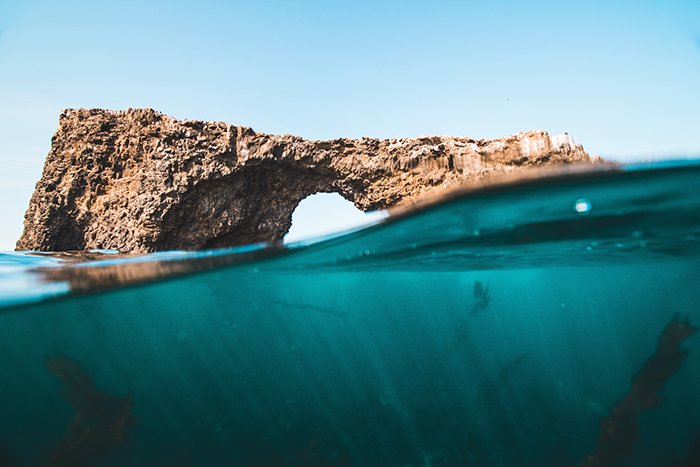 Una foto submarina mitad arriba, mitad abajo de una formación rocosa en el mar