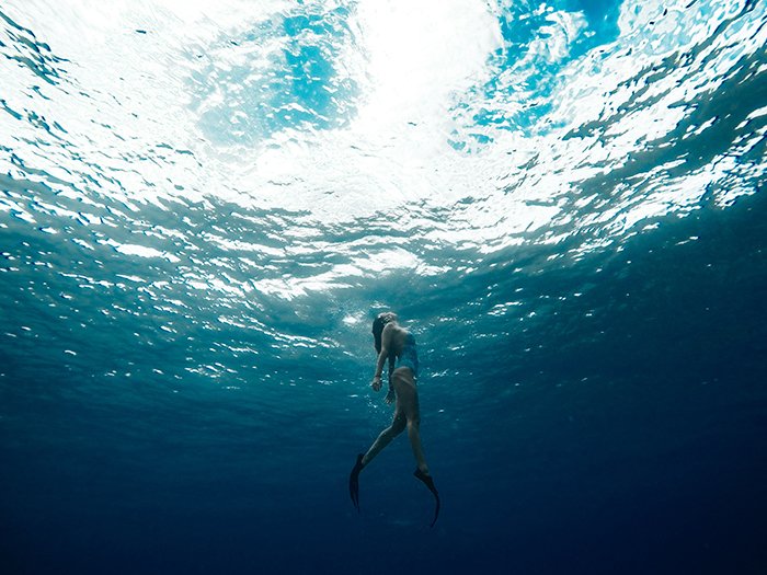 Genial retrato submarino de una niña nadando hacia la superficie