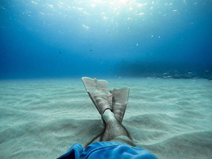 Genial retrato submarino de un nadador con las piernas cruzadas