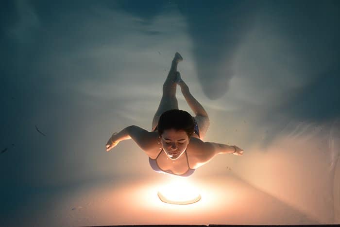 un impresionante retrato submarino de una nadadora posando sobre una luz cálida
