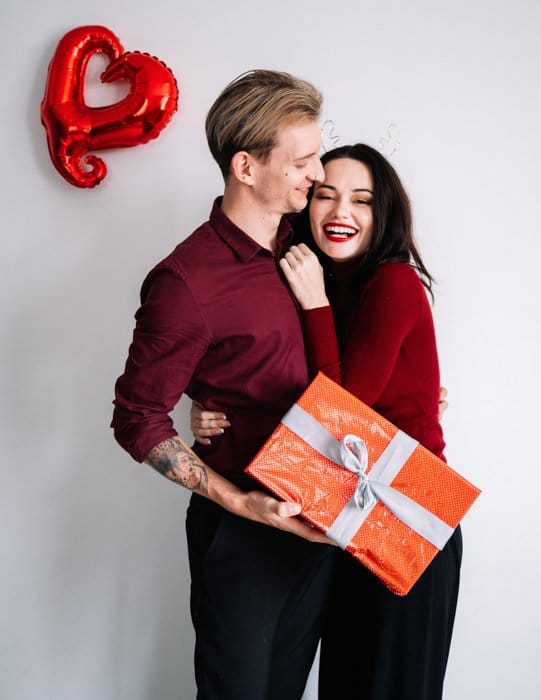 Imagen de una linda pareja en el día de San Valentín sosteniendo un regalo