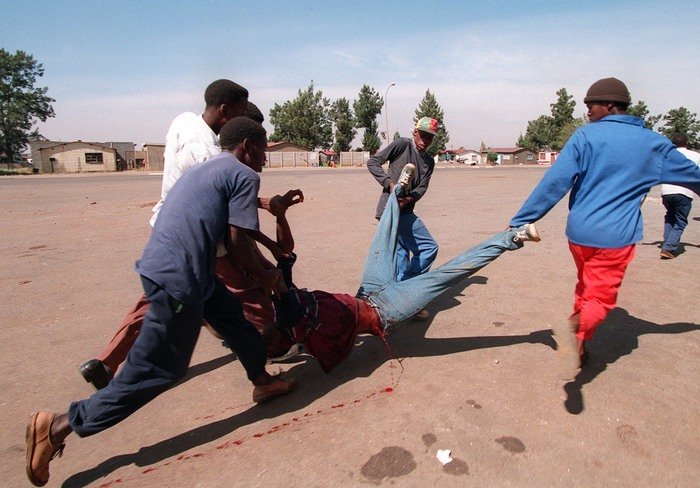 Una imagen de 5 hombres cargando a un hombre sangrando por el fotógrafo de guerra João Silva