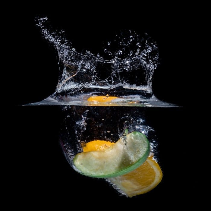 Una rodaja de fruta fotografiada mientras cae al agua y crea un chapoteo