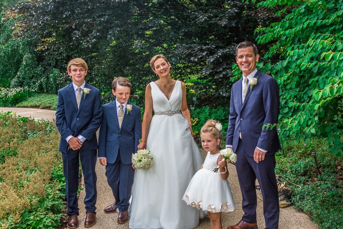 familia de bodas, novia, novio y 3 niños, de pie en un camino con arbustos y árboles detrás de ellos, edición de fotos de boda HDR
