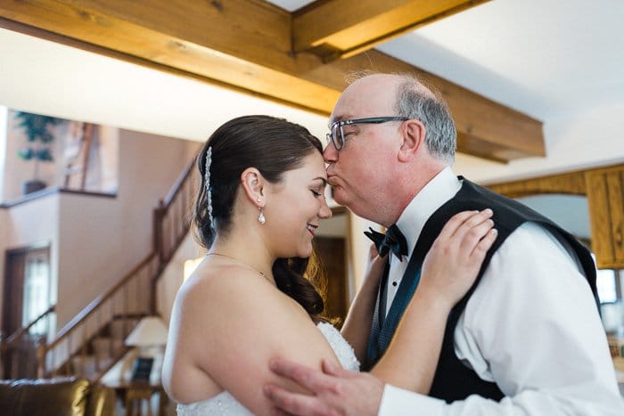 Hermoso momento de padre besando la cabeza de la novia capturado por el fotógrafo de bodas