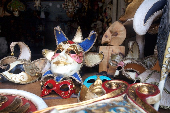 Una colección de máscaras festivas venecianas en un escaparate: los mejores consejos para la fotografía de Venecia