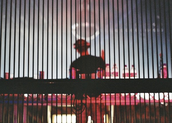 Foto borrosa de una persona en un escenario tomada desde detrás de las rejas, que demuestra el uso de líneas verticales en la composición fotográfica.
