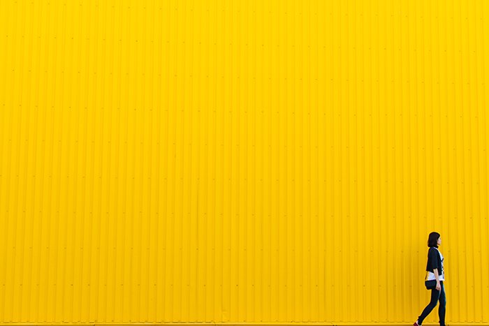 Colorido retrato de una modelo femenina que pasaba por una pared de color amarillo brillante, usando colores vibrantes en la fotografía