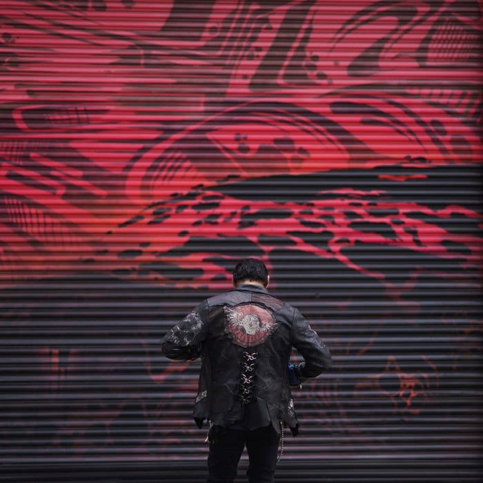 Foto de un hombre con una chaqueta de cuero delante de un fondo abstracto