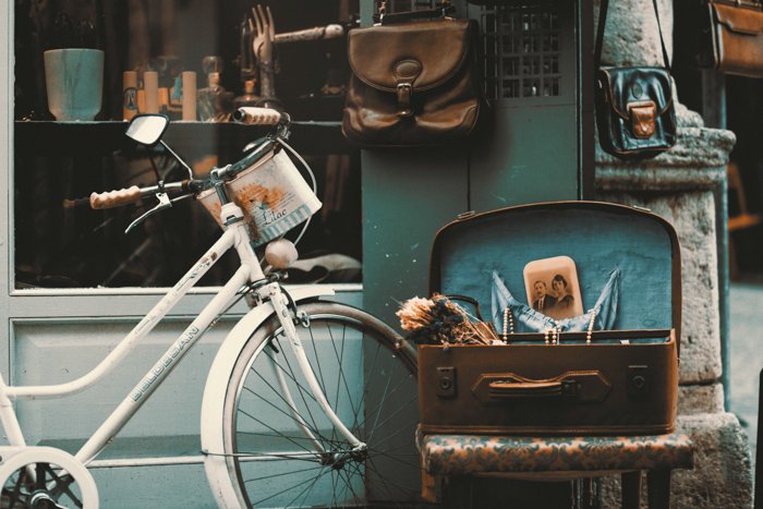 una naturaleza muerta al aire libre de antigüedades como una bicicleta, bolsos de cuero y fotos - consejos de fotografía vintage
