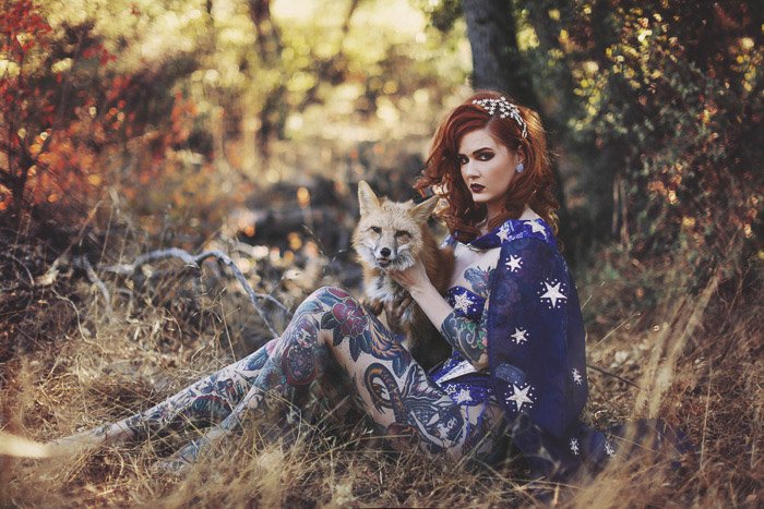 Un modelo de mujer tatuada posando al aire libre con un zorro