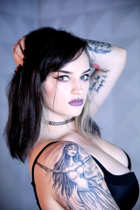 Primer plano de una modelo de mujer tatuada posando en el interior - sesión de fotos de tatuajes
