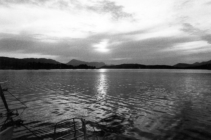 Un disparo sereno de un lago con montañas en el fondo filmado en película en blanco y negro