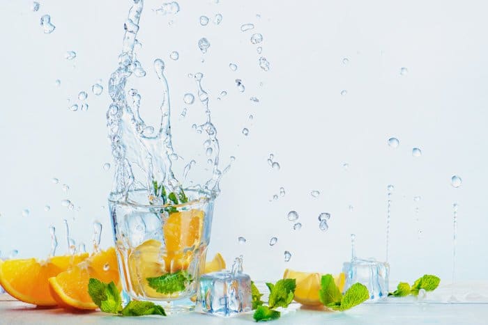 una fotografía creativa de comida con naranjas y salpicaduras de agua sobre fondo blanco