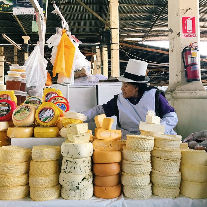 Hombre en un mercado que vende rondas de queso entero- estilos de fotografía de teléfonos inteligentes
