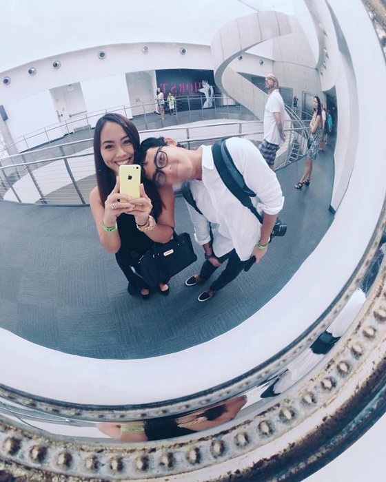 Pareja tomando selfie a través de un espejo circular en un centro comercial