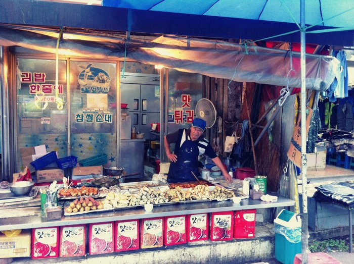 Foto de la calle de un vendedor cuidando su comida.
