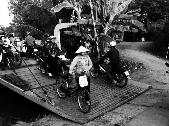 Una foto callejera en blanco y negro de personas saliendo de un ferry con bicicletas