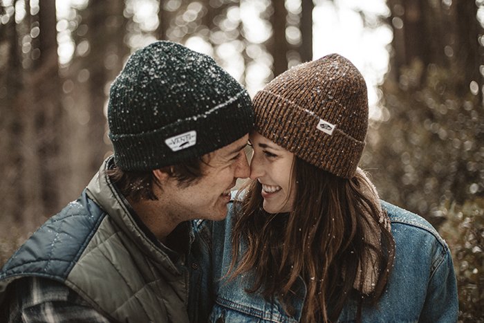 Una pareja alegre y sonriente en la nieve - sonrisa para la cámara
