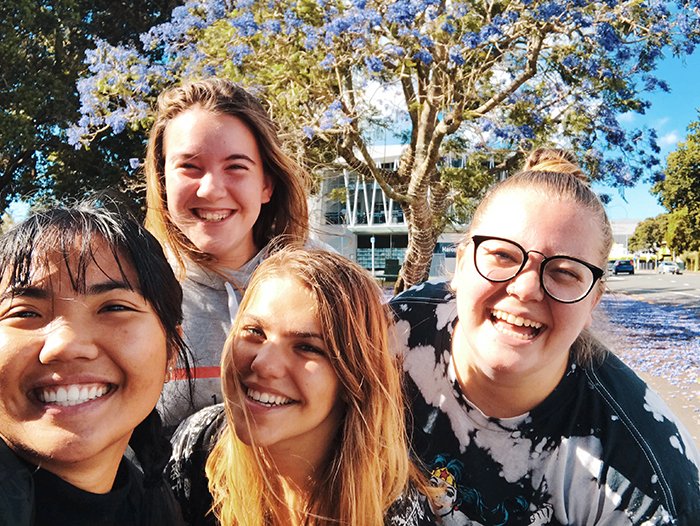 Un selfie de grupo de personas sonrientes al aire libre.