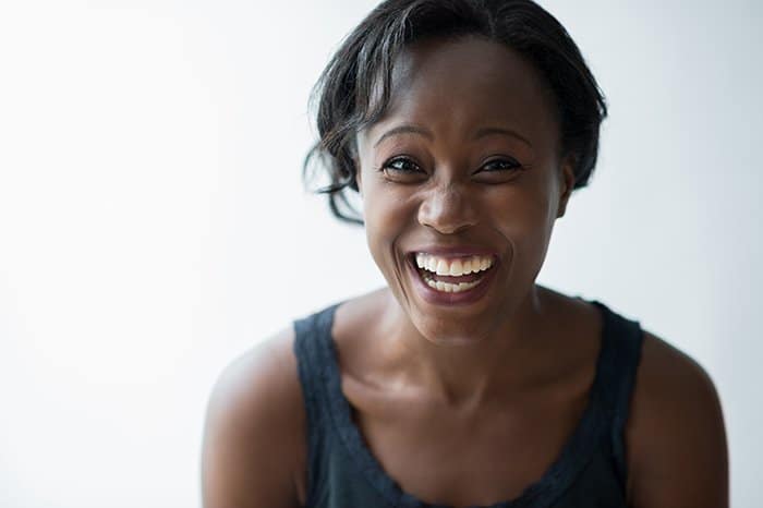 Una mujer riendo sobre un fondo blanco: sonríe para los consejos de la cámara