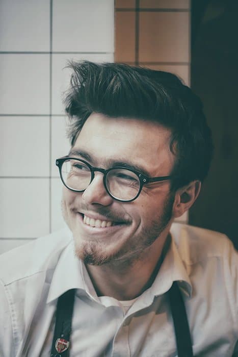 Un retrato de un hombre con gafas sonriendo natural