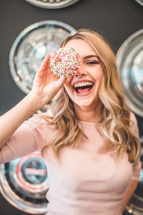 Divertido retrato de una modelo femenina riendo sosteniendo un pastel en su ojo - cómo sonreír para fotos