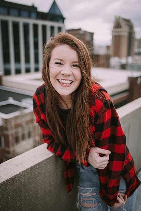 Divertido retrato de una modelo femenina riendo posando en una azotea urbana - cómo sonreír para fotos