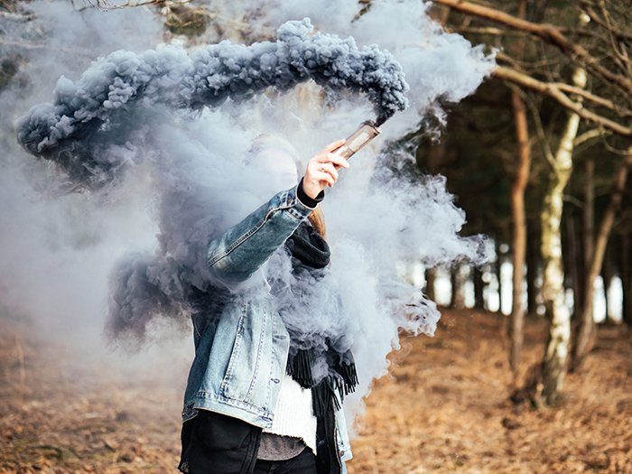 Asmoke bomb fotografía retrato de una mujer sosteniendo una granada de humo azul cerca de su cara