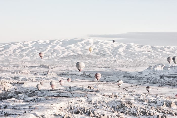 Muchos globos aerostáticos en vuelo sobre un paisaje nevado