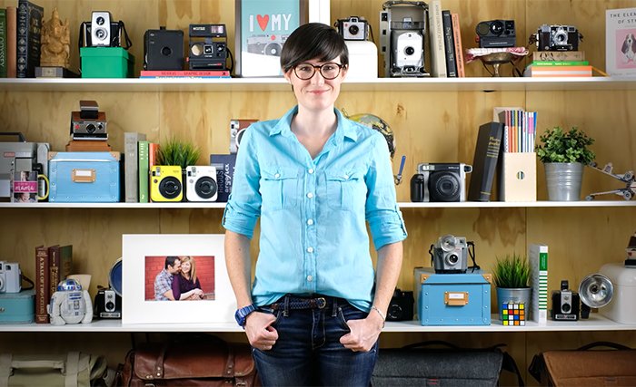 Foto de una mujer de pie frente a estantes llenos de cámaras