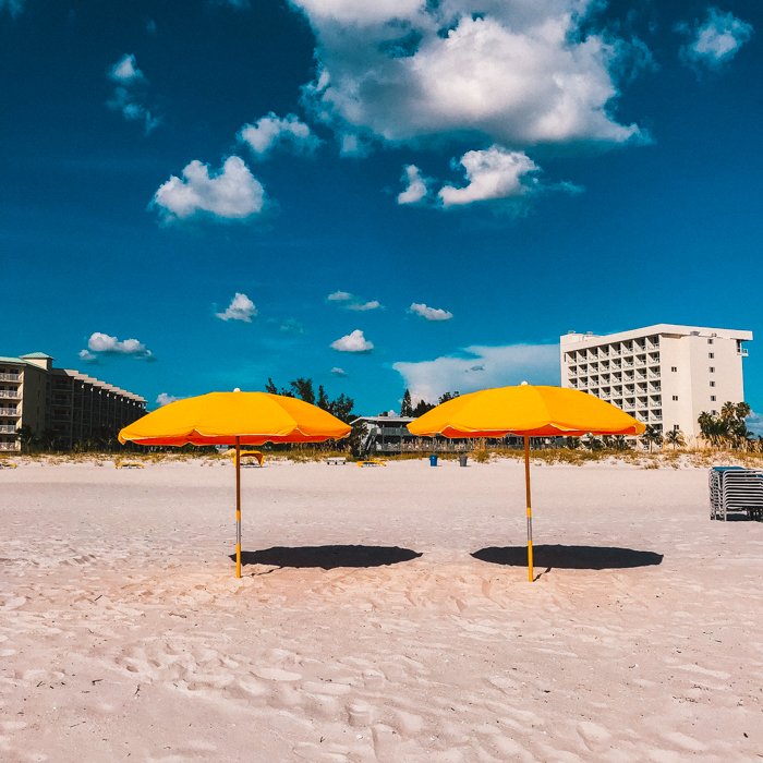 Una foto de una composición de playa con dos sombrillas naranjas en el medio.