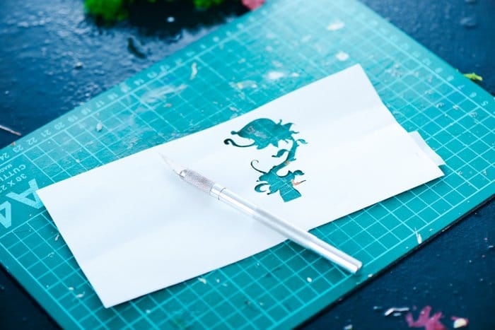 una silueta recortada de una flor en un trozo de papel sobre una estera de corte