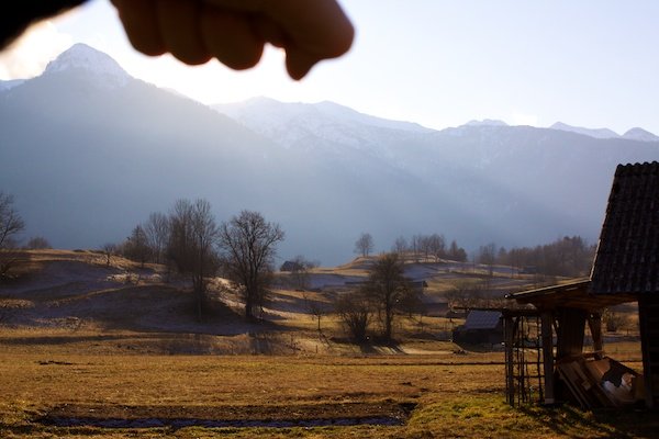 una mano bloqueando el sol con montañas eslovenas en el fondo