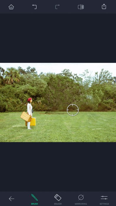Captura de pantalla de la aplicación de retoque táctil, una mujer con sombrero rojo y bolsas amarillas de pie en el campo, con la herramienta Pincel visible