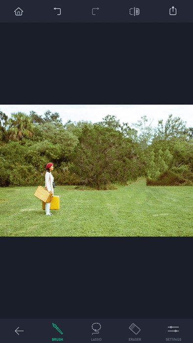 Captura de pantalla de la aplicación de retoque táctil, una mujer con sombrero rojo y bolsas amarillas de pie en el campo