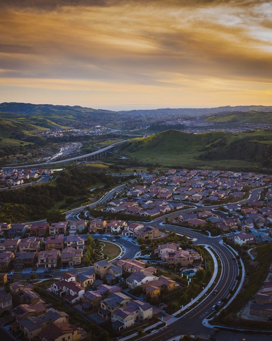Foto de drone de una ciudad con colinas al atardecer