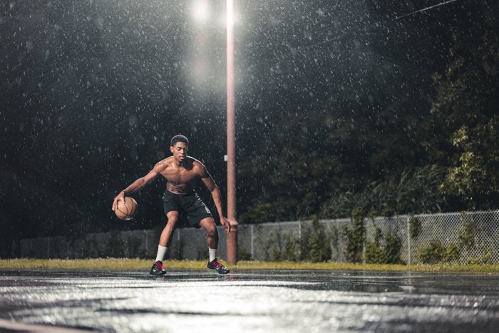 Fotografía de lluvia atmosférica de un hombre jugando baloncesto por la noche