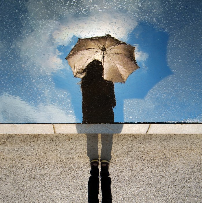 Foto de lluvia creativa de una persona sosteniendo un paraguas, reflejada en una ventana salpicada de lluvia