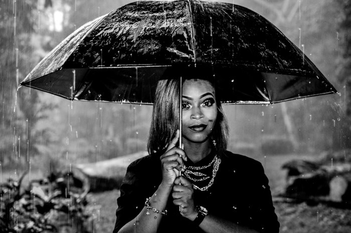 Retrato en blanco y negro de una mujer sosteniendo un paraguas bajo la lluvia