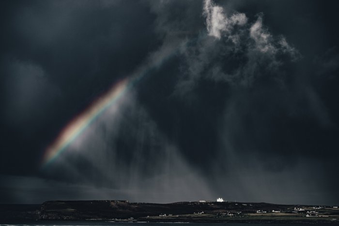 Un paisaje espectacular con un arco iris rompiendo un cielo tormentoso