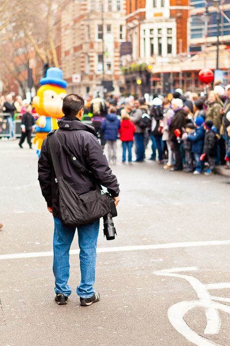Un hombre que sostiene una cámara réflex digital mirando a la multitud en un carnaval