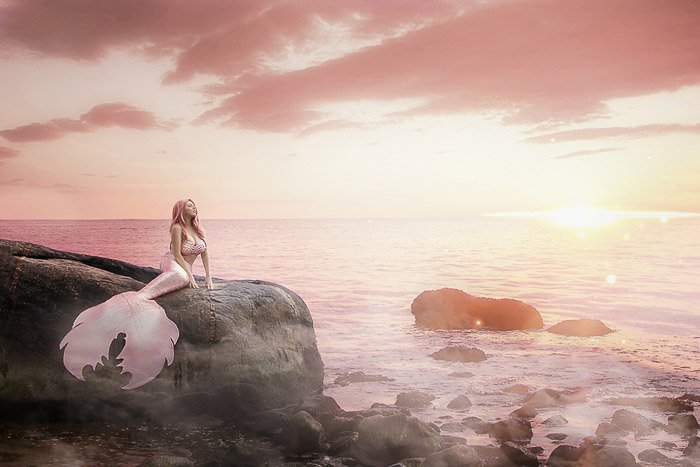 Fotografía de tocador de autorretrato de ensueño de una modelo femenina posando en una cola de sirena junto al mar